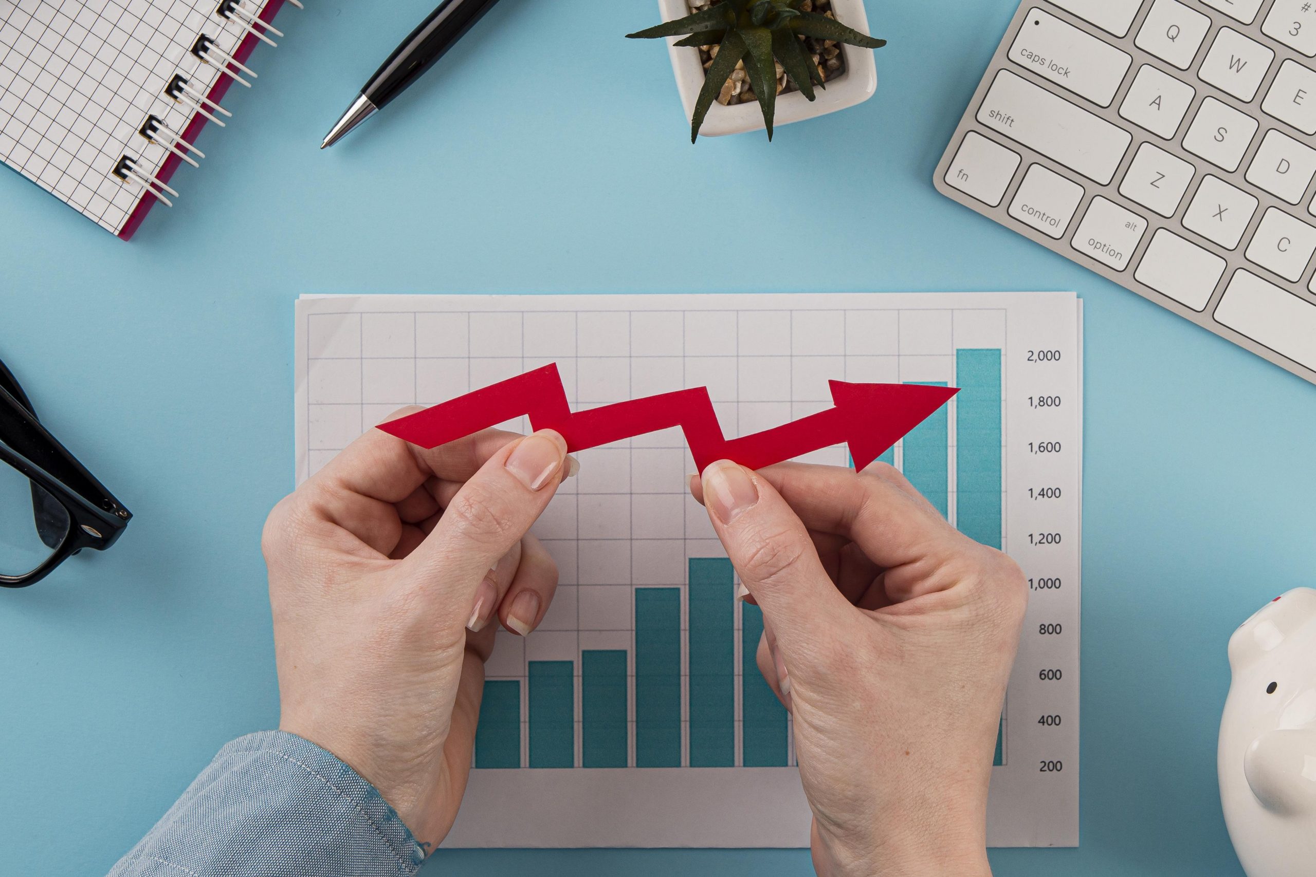 top-view-of-business-items-with-growth-chart-and-hands-holding-arrow